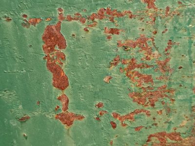 Green paint flakes away, orange grit claims the surface, time leaves a thick mark
