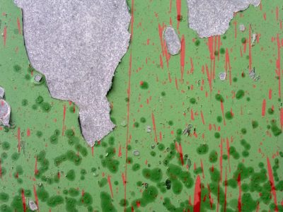 Green skin curls away, red splatters bleed down the wall, grey stone waits behind