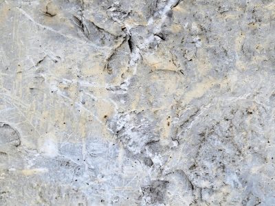 Grey concrete is scarred, fine lines cross the weathered face, ancient dust remains