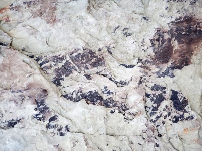 Grey grains flow through deep, industrial ridges hold, grit marks the pattern