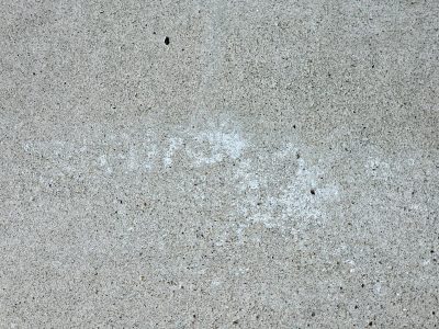 Grey grains hold the light, white ghost fades on rough concrete, silent stone endures