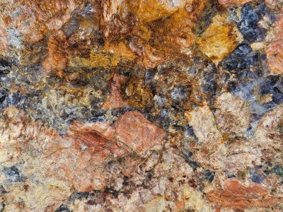 Crystals locked in time, orange veins across the grey, jagged stone reveals