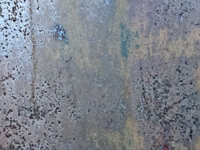 Grey pits mark the light, ancient paths trace the surface, grit claims the metal