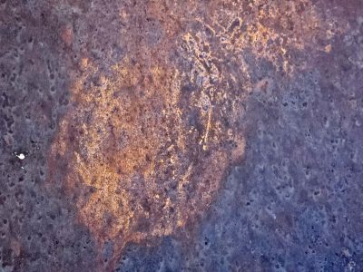 Iron meets the air, orange blooms on purple skin, time eats through the steel