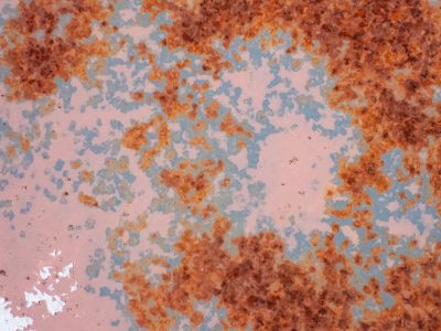 Rust blooms on the pink, metal flakes in teal and red, time eats through the paint