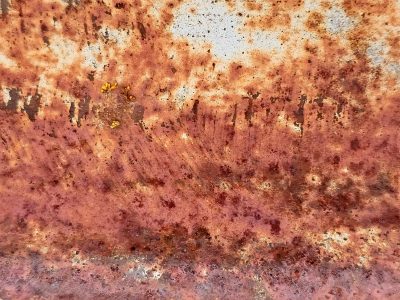 Heavy rust takes hold, orange flakes on weathered steel, metal fades away