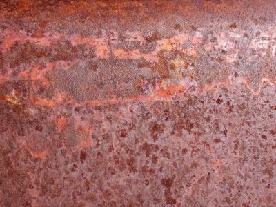 Iron turns to dust, orange blooms across the steel, time eats through the sheet