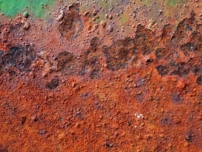 Iron yields to time, orange crust bubbled and raw, green paint flakes away