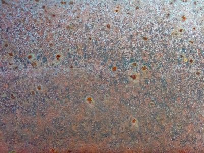 Lime skin flakes away, dark trails trace the heavy, light carves the metal