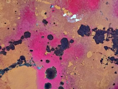 Magenta and gold, pitted metal shows its age, oxidation creeps