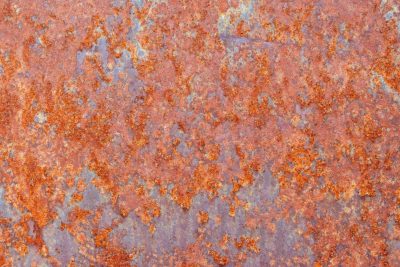 Orange blooms on steel, iron yields to heavy rust, texture of decay