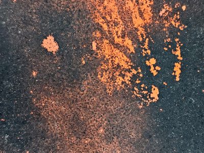 Orange dust on road, dark surface holds the bright hue, grit meets vibrant paint