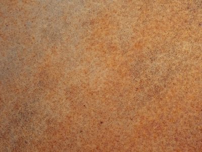 Orange iron blooms, oxidation eats the steel, grains of dust remain