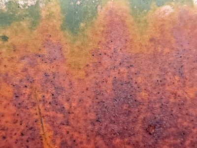 Orange rust takes hold, green paint yields to time's decay, metal turns to dust