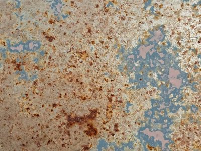 Orange rust takes hold, grey islands drift on metal, time devours the steel