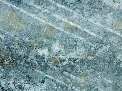 Pale lines mark the stone, frost clings to the textured grain, winter's cold embrace