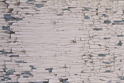 Pale paint starts to curl, grey wood peeks through jagged lines, age reveals the core