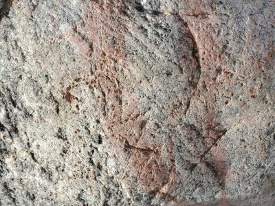 Pale stone holds the sun, pink veins run through granite skin, time etches the face