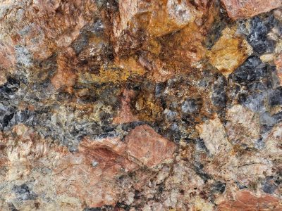 Pink crystals locked tight, grey veins cut through solid earth, deep stone holds its form