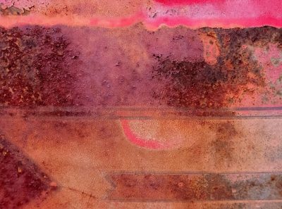 Pink layers fade down, rusty edges meet the light, grit marks the metal