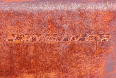 Red fields hold the name, heavy grit claims the script, time marks the metal