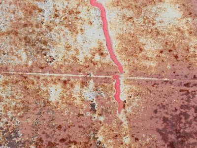 Red line carves the white, rust trails trace the heavy metal, light marks the surface