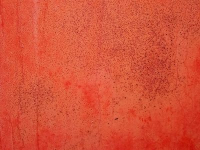 Red paint starts to fade, dark spots cover the surface, tiny cracks emerge