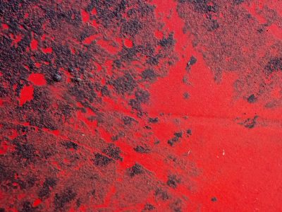 Red paint starts to flake, blackened iron shows beneath, decay claims the shell