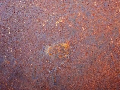 Red rust coats the steel, iron blooms in mottled brown, time eats through the core