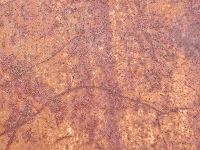 Red rust eats the steel, ancient patterns etched in time, metal yields to air