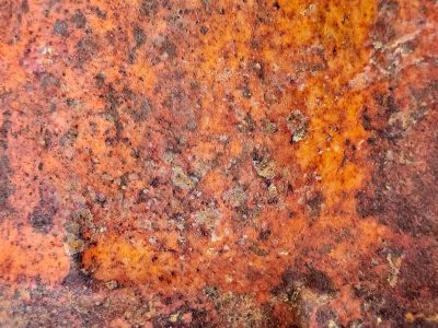 Orange rust takes hold, iron bleeds across the plate, decay eats the steel