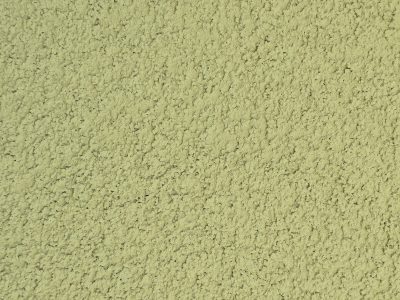 Rough green stucco wall, shadows dance on bumpy grit, uniform landscape
