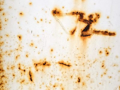 Rust blooms on the white, iron scars the painted sheet, metal starts to turn