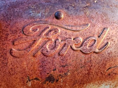 Rusty script holds tight, time claims the heavy finish, grit marks the Ford skin