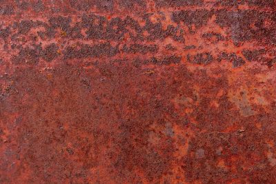 Crimson oxide blooms, rough decay on heavy steel, time consumes the plate