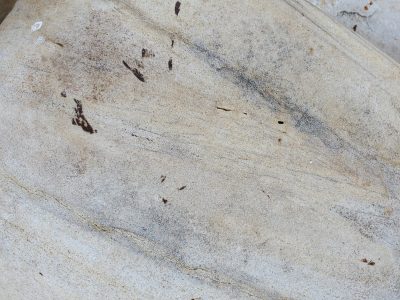 Smooth beige stone curved round, dark veins trace across the face, time flows through the grain