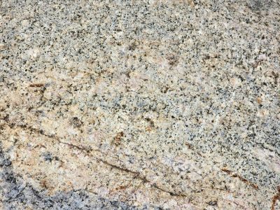 Speckled granite face, grains of salt and pepper earth, ancient veins run deep