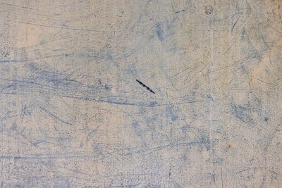 Tan skin has light marks, jagged scars trace the metal, grit marks the finish