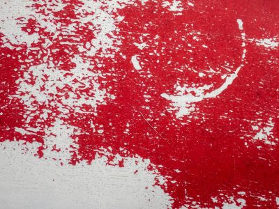 Red flakes peel away, white base breaks the crimson tide, weathered skin shows wear