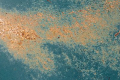 Teal paint fades away, orange rust blooms on the steel, time eats through the coat