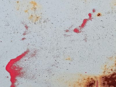 White paint bears the scars, crimson splashes mar the steel, rust blooms in corners