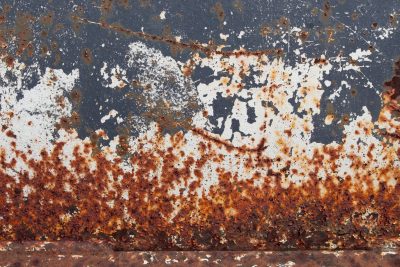 White paint flakes away, orange rust consumes the wall, metal turns to dust