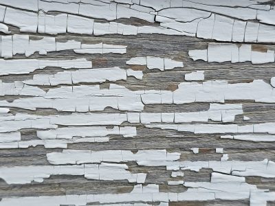 White paint flakes away, weathered grain reveals the age, fragments of the past