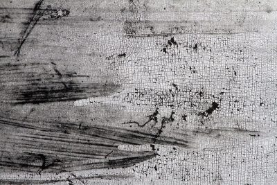 White skin flakes away, black scars trace the heavy field, grit marks the finish