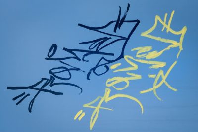 Yellow arcs on blue, black marks trace the metal skin, light holds the found tag