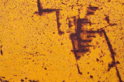 Yellow skin decays, dark iron bleeds through the paint, cryptic marks remain