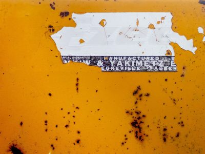 Yellow fields meet white, faded labels peel away, dark spots mark the skin