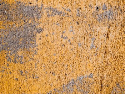 Yellow paint wears thin, rough grey stone hides underneath, time scrapes at the edge