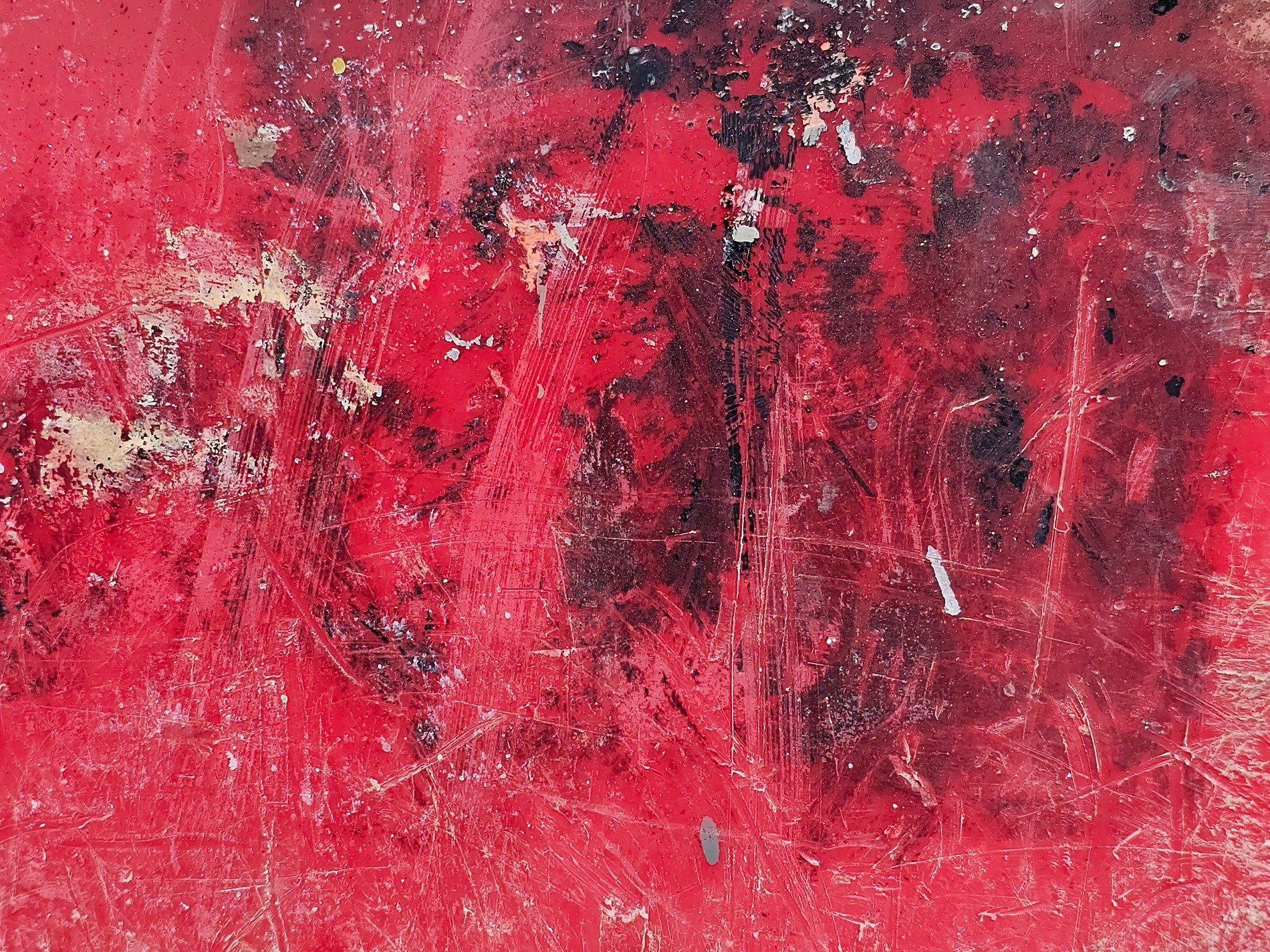 Vibrant red paint scars, black stains bloom in jagged lines, worn surface tells tales