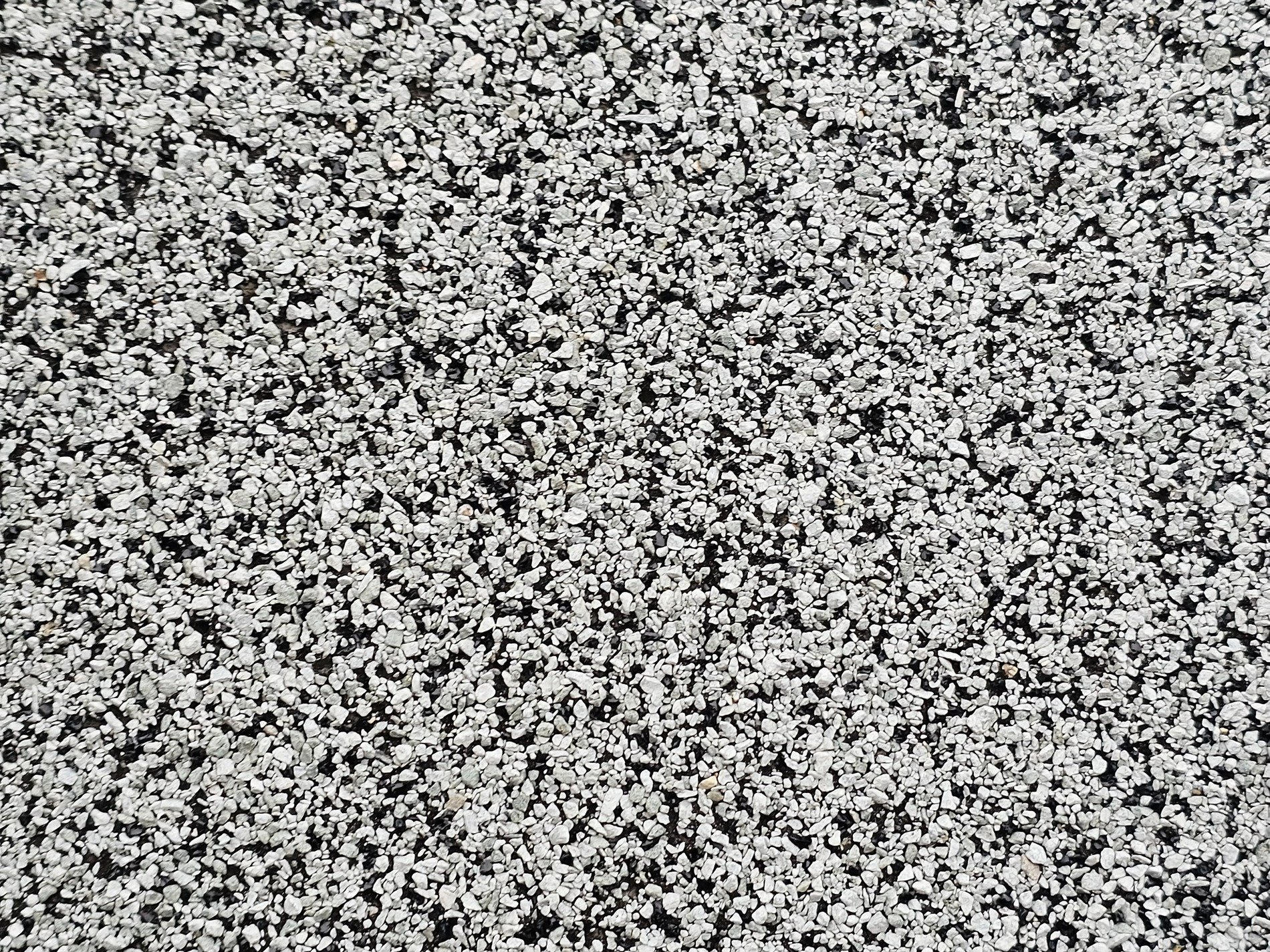 White grit on the road, scattered patterns in the dark, rough path waits below